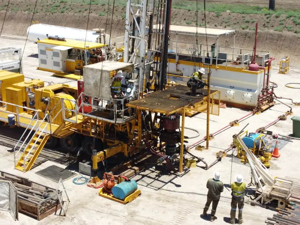 Group of workers engaged in well servicing activities on rigs, wearing safety gear and operating machinery